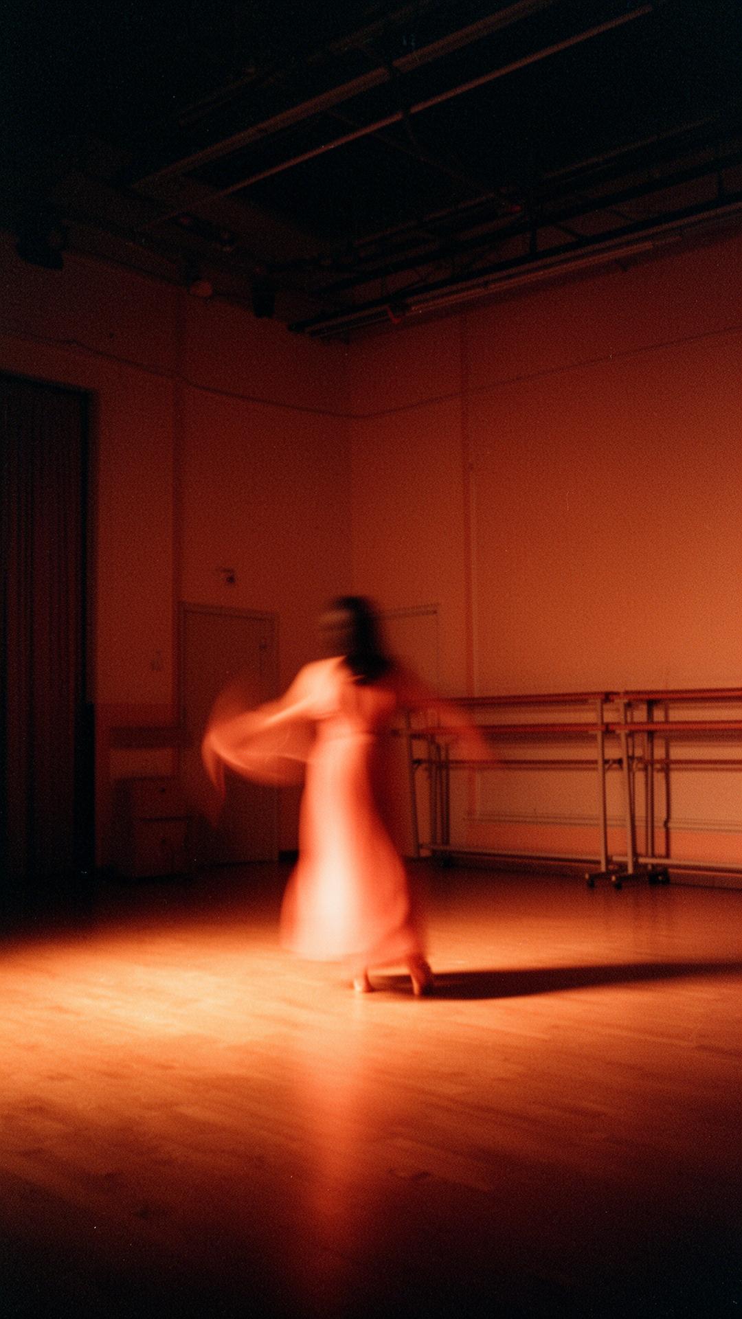 Figura en movimiento dentro de un espacio teatral cálido